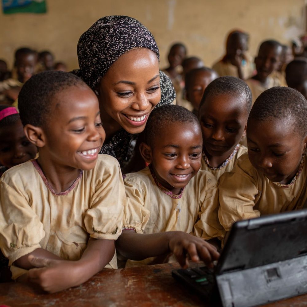 Une enseignante et ses élèves devant un ordinateur portable, en classe